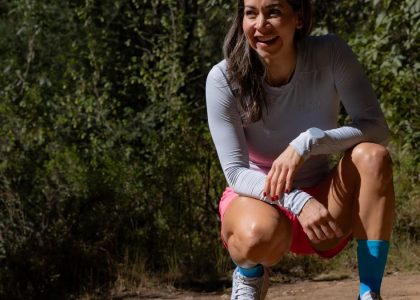 Smiling woman in sportswear takes a break during an outdoor workout, surrounded by nature.